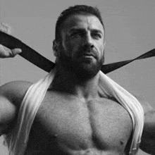 a shirtless man with a beard is wearing a tie and a towel around his neck .