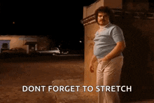 a man with a mustache is standing in front of a building at night and saying `` dont forget to stretch '' .