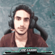 a man wearing headphones is sitting in front of a screen that says joe gaming
