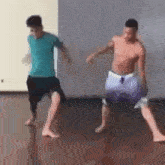 two men are dancing barefoot on a wooden floor in a gym .