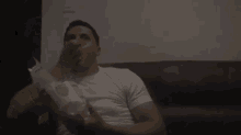 a man is sitting on a couch eating a bag of mcdonald 's hamburgers