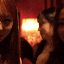 three women are standing next to each other in a dark room .