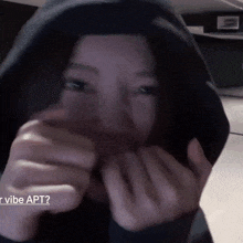 a woman wearing a hoodie is covering her face with her hands .