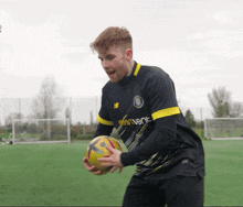 a man holding a soccer ball wearing a jersey that says skyventure