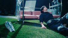 a man laying on the grass with a bottle of coca cola