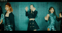 a group of young women are dancing in front of a wall .