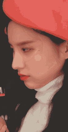 a close up of a woman wearing a red hat and a white turtleneck