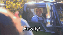 a man in a cowboy hat is sitting in the driver 's seat of a truck that says howdy