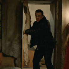 a man in a black leather jacket holds a large piece of wood