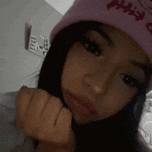 a girl wearing a pink hello kitty beanie is taking a selfie .