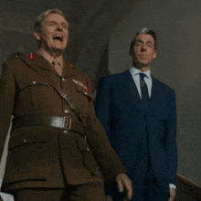 a man in a military uniform stands next to another man in a suit and tie