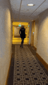 a woman in a black dress is walking down a hallway with a sign that says exit