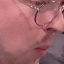 a close up of a man 's face wearing glasses and making a funny face .