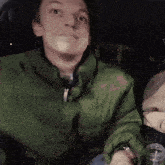 a man wearing a green jacket looks at the camera
