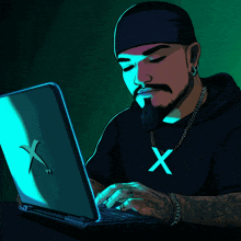 a man with a beard is typing on a laptop with the letter x on his shirt