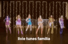 a group of women are standing next to each other on a dance floor in front of a row of lights .
