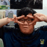 a man wearing glasses making a peace sign