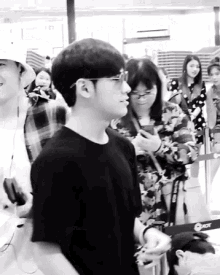 a black and white photo of a man wearing glasses standing next to a woman .