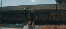 a person riding a skateboard in front of a wall with graffiti on it