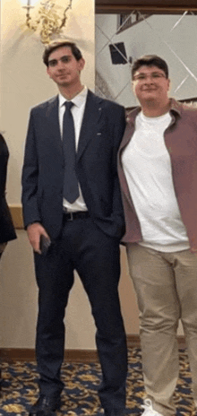 a man in a suit stands next to another man in a white shirt