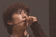 a young man wearing a microphone and a necklace is singing into it .