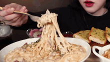 a woman is holding a fork over a bowl of spaghetti