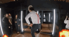 a man in a hat and suspenders is dancing in a room