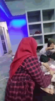 a woman in a red hijab is sitting at a table with other people