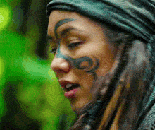 a woman with a tattoo on her face looks at the camera