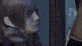 a close up of a person 's face with purple paint on it looking out of a window .