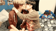 two people kissing on a bed with one wearing a shirt that says spiderman