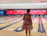 a woman stands in front of a bowling alley with a sign that says takaneko-tv