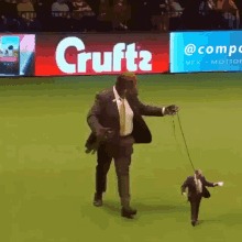 a man in a suit is walking a smaller man on a leash in front of a cruft 's ad