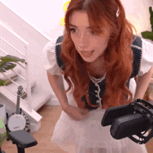 a woman with red hair is standing in front of a microphone holding a cell phone .