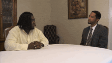 a man in a suit sits at a table with two other men