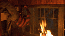 a person is standing in front of a window with a fire behind them