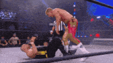 two men are wrestling in a ring with a referee and a sign that says aew on it