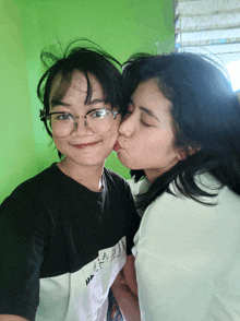 a girl kissing another girl on the cheek while wearing a t-shirt that says hawaii