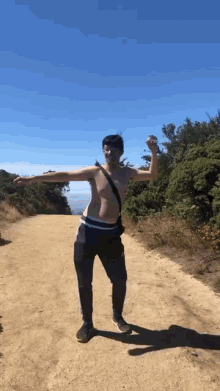 a man without a shirt is standing on a dirt road