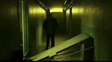 a silhouette of a person walking down a hallway with a yellow light .