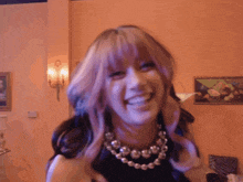 a woman with purple hair and a necklace is smiling