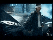 a man with a bandage on his head is standing in front of a car .