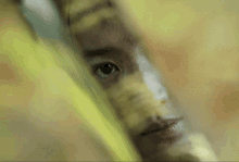 a close up of a person 's face behind a yellow curtain