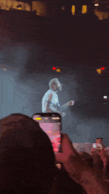 a man in a white shirt is playing a guitar on stage