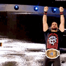 a wrestler with his arms in the air wearing a t-shirt that says ' raw ' on it