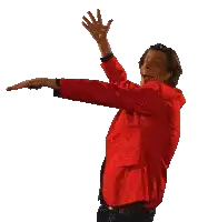a man in a red jacket is dancing with his arms in the air