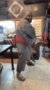 a bald man in a kimono is standing in a living room .