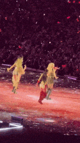 a group of women are dancing on a stage with a crowd behind them