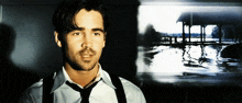 a man in a white shirt and black tie stands in front of a picture of a lake