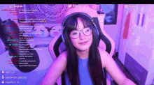 a woman wearing glasses and headphones is smiling in front of a screen that says twitch